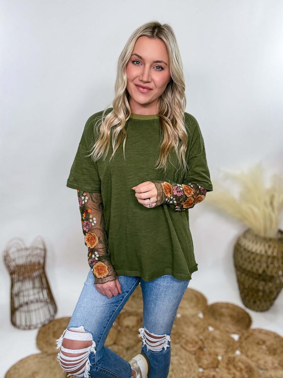 In Loom Oversized olive green tee with layered sheer embroidered floral lace mesh sleeves. Relaxed fit, earthy olive tone, and high-quality fabric blend. Perfect for casual fall outfits or dressing up with jeans or leather leggings. Feminine and edgy design ideal for crisp autumn days.