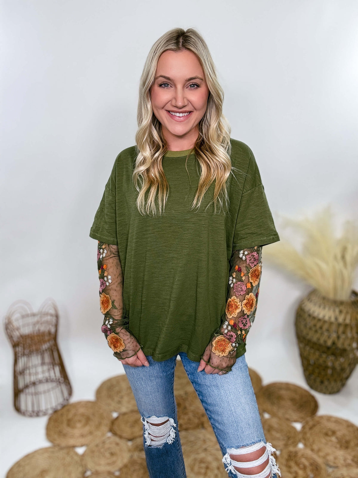 In Loom Oversized olive green tee with layered sheer embroidered floral lace mesh sleeves. Relaxed fit, earthy olive tone, and high-quality fabric blend. Perfect for casual fall outfits or dressing up with jeans or leather leggings. Feminine and edgy design ideal for crisp autumn days.