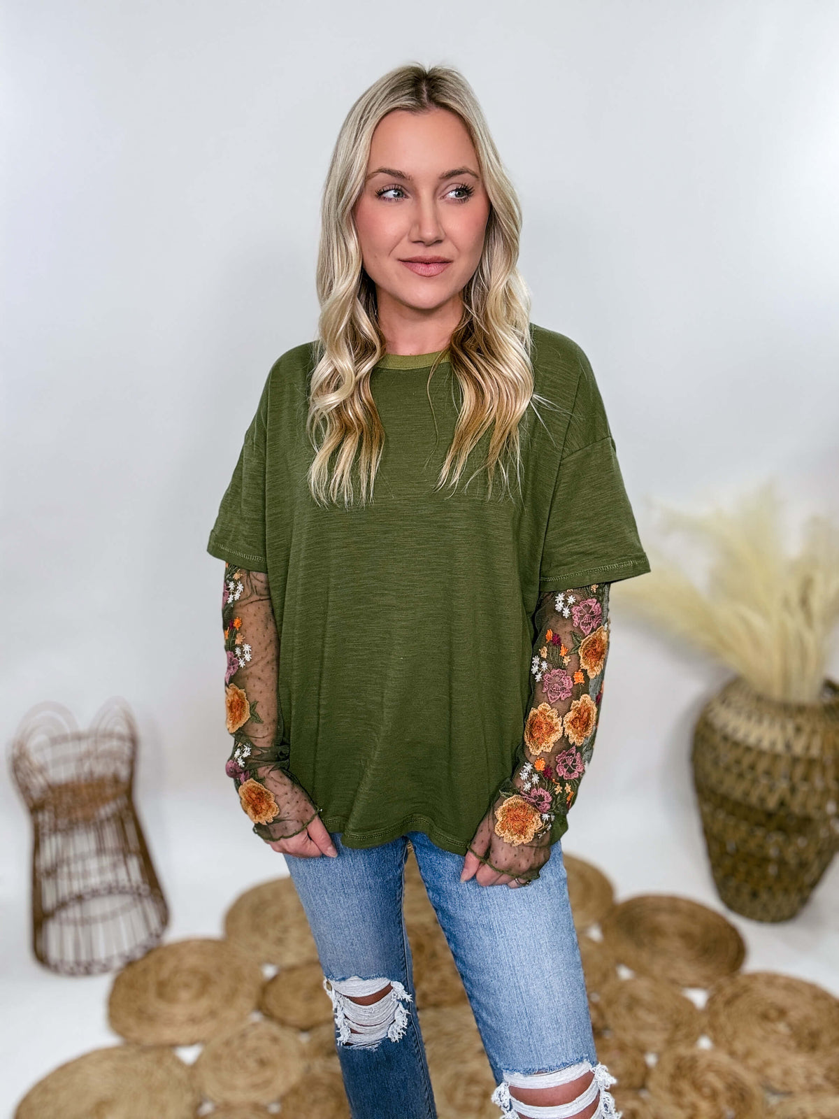 In Loom Oversized olive green tee with layered sheer embroidered floral lace mesh sleeves. Relaxed fit, earthy olive tone, and high-quality fabric blend. Perfect for casual fall outfits or dressing up with jeans or leather leggings. Feminine and edgy design ideal for crisp autumn days.