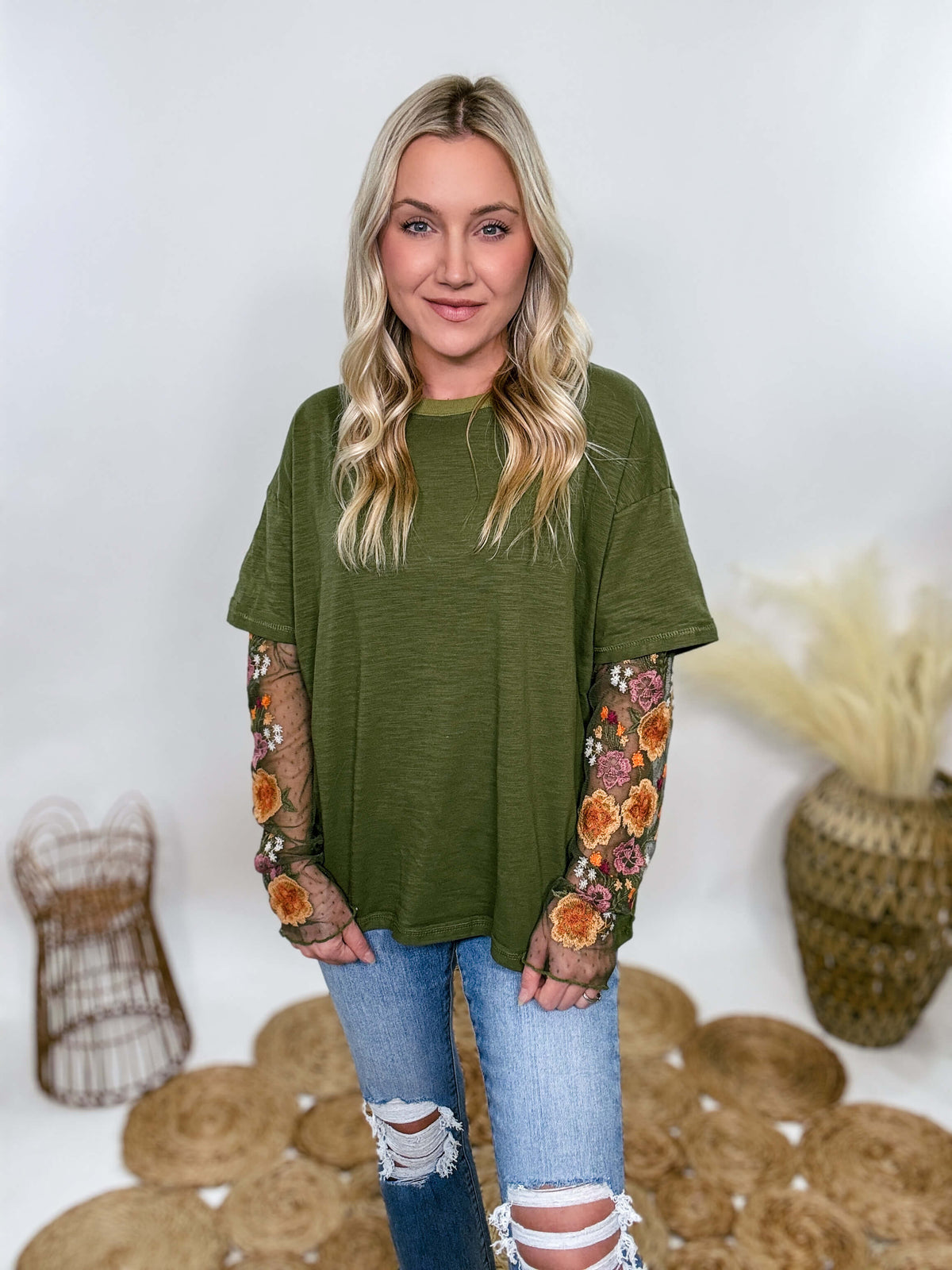 In Loom Oversized olive green tee with layered sheer embroidered floral lace mesh sleeves. Relaxed fit, earthy olive tone, and high-quality fabric blend. Perfect for casual fall outfits or dressing up with jeans or leather leggings. Feminine and edgy design ideal for crisp autumn days.