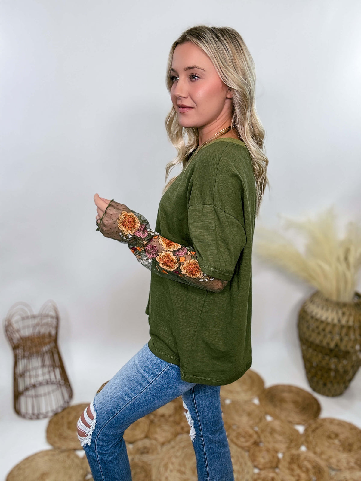 In Loom Oversized olive green tee with layered sheer embroidered floral lace mesh sleeves. Relaxed fit, earthy olive tone, and high-quality fabric blend. Perfect for casual fall outfits or dressing up with jeans or leather leggings. Feminine and edgy design ideal for crisp autumn days.