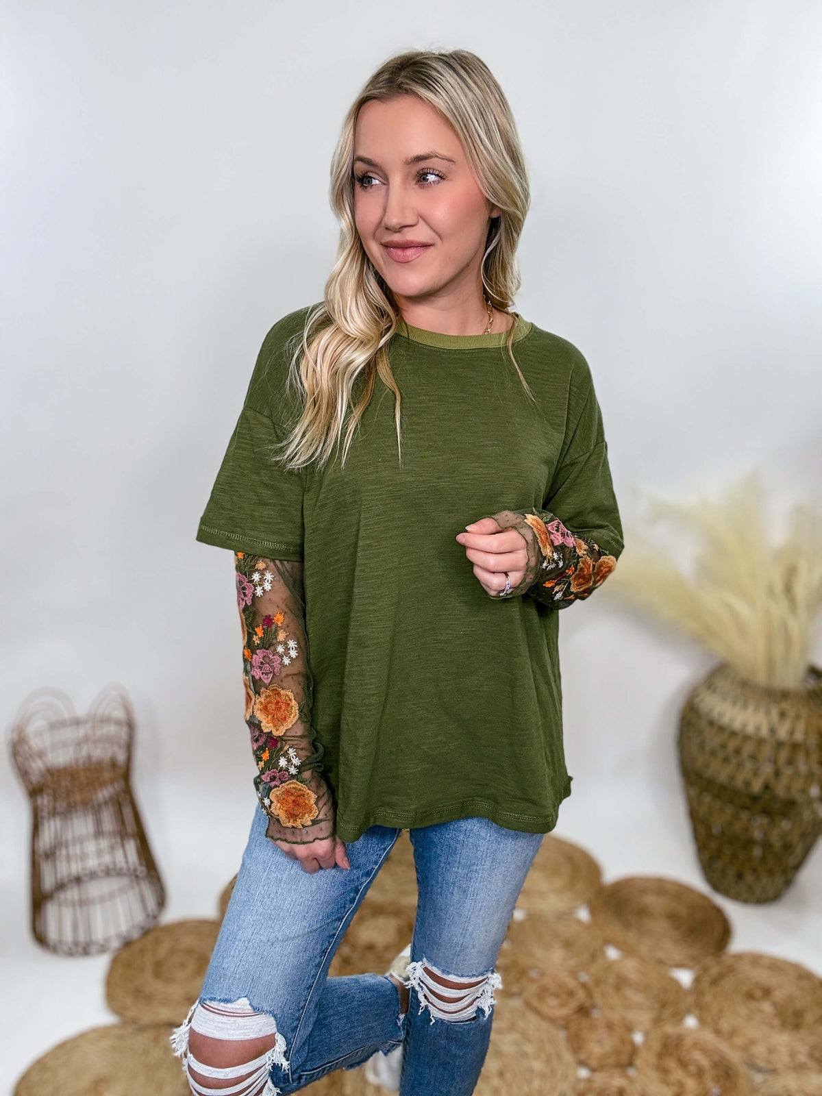 In Loom Oversized olive green tee with layered sheer embroidered floral lace mesh sleeves. Relaxed fit, earthy olive tone, and high-quality fabric blend. Perfect for casual fall outfits or dressing up with jeans or leather leggings. Feminine and edgy design ideal for crisp autumn days.