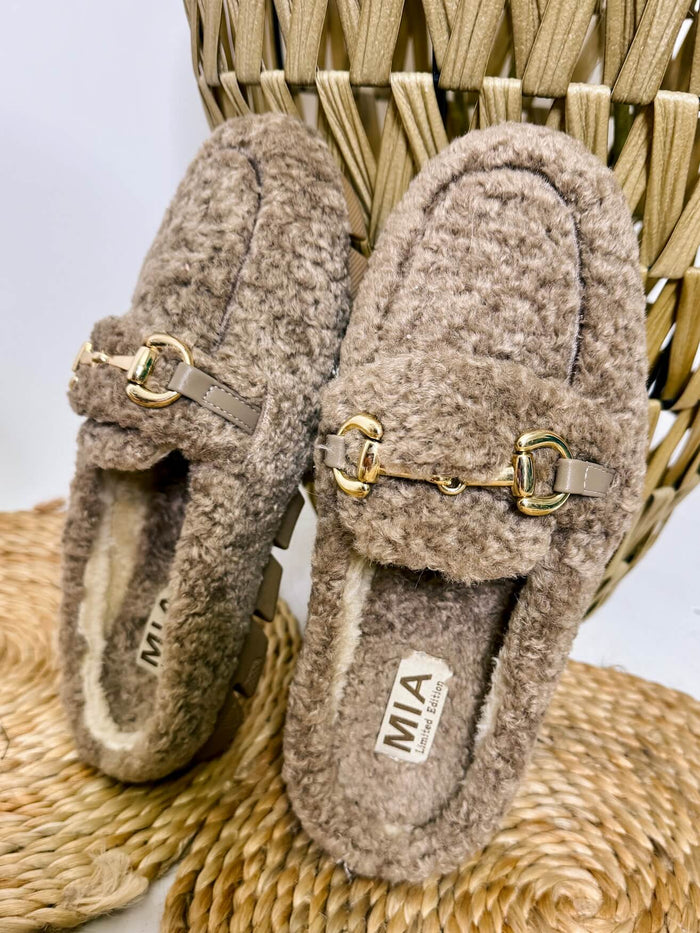 MIA limited edition cocoa faux sherling slipper mule. Cocoa faux shearling mules with fur lining, gold buckle accent, and rubber outsole, ideal for lounging or casual outings.