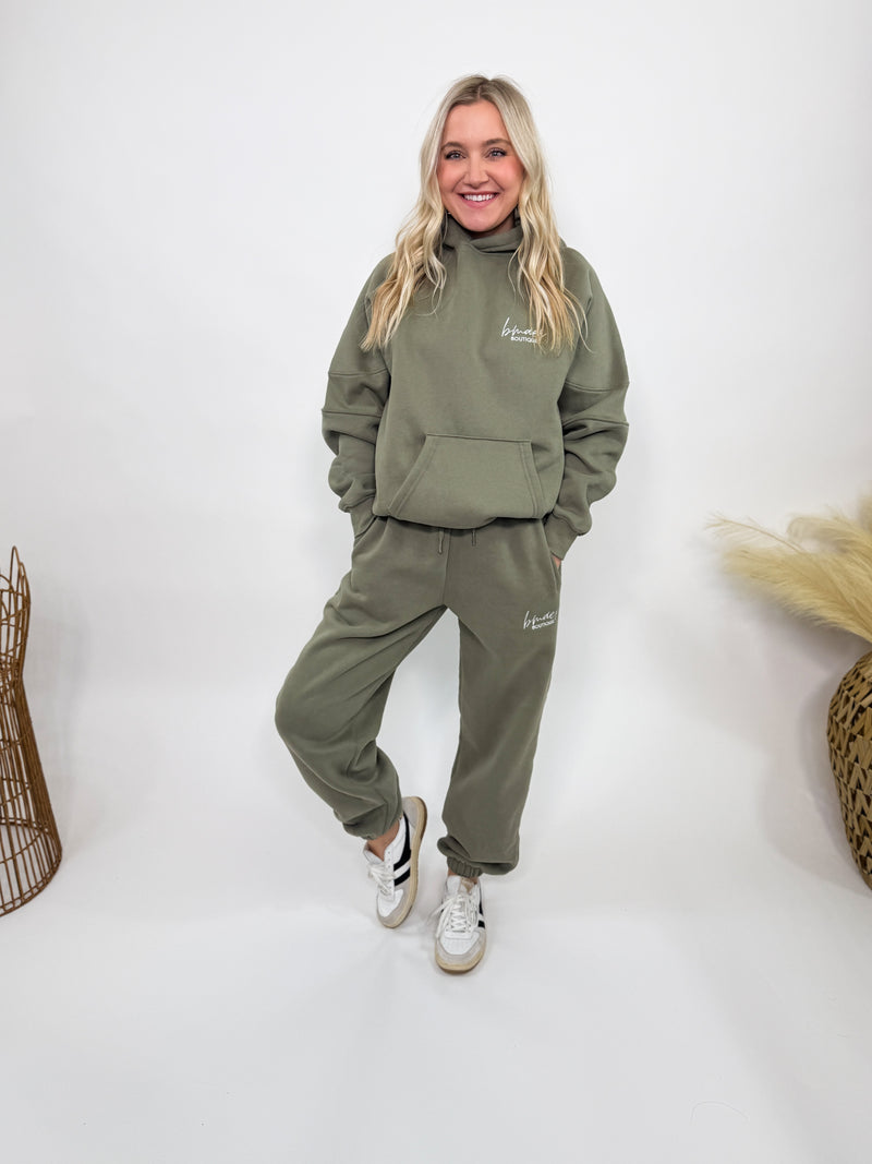 Olive green fleece-lined luxury lounge Bmaes hoodie with embroidered Bmaes Boutique logo, drop shoulders, kangaroo pocket, and ribbed details. Perfect for cozy lounging or pairing with the matching joggers for a stylish, warm set from Bmaes Boutique.