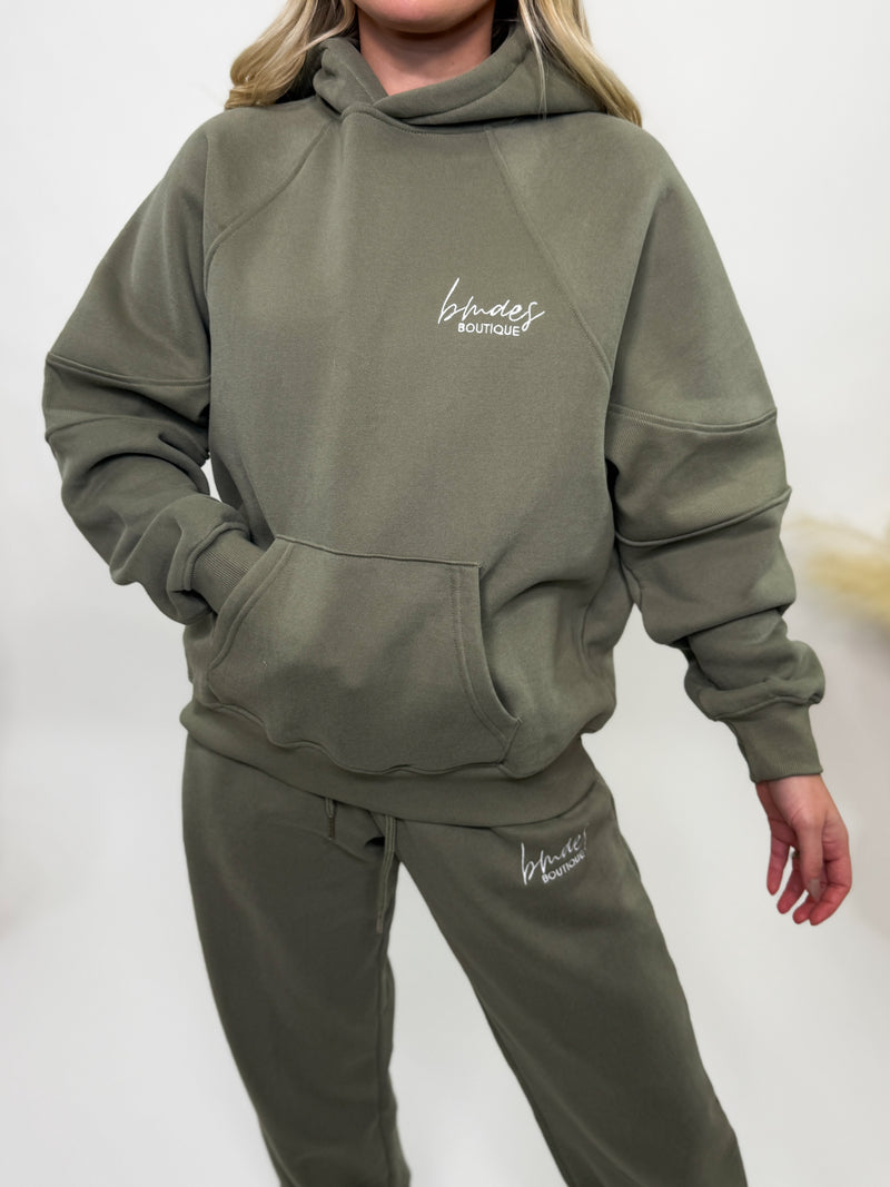 Olive green fleece-lined luxury lounge Bmaes hoodie with embroidered Bmaes Boutique logo, drop shoulders, kangaroo pocket, and ribbed details. Perfect for cozy lounging or pairing with the matching joggers for a stylish, warm set from Bmaes Boutique.