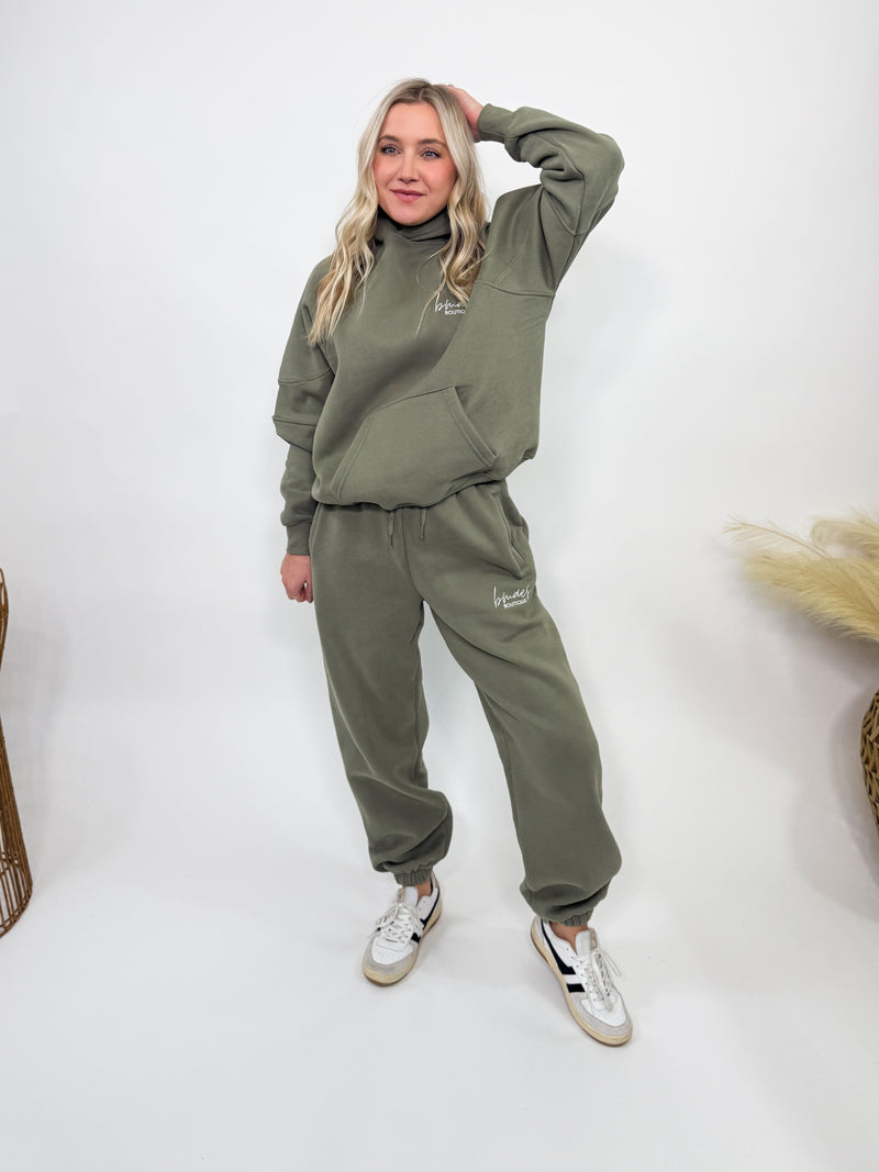 Olive green fleece-lined luxury lounge Bmaes hoodie with embroidered Bmaes Boutique logo, drop shoulders, kangaroo pocket, and ribbed details. Perfect for cozy lounging or pairing with the matching joggers for a stylish, warm set from Bmaes Boutique.