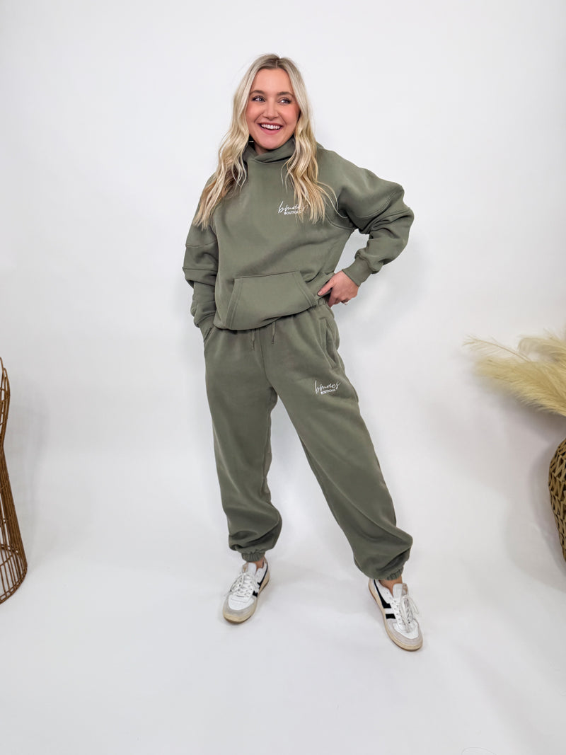 Olive green fleece-lined luxury lounge Bmaes hoodie with embroidered Bmaes Boutique logo, drop shoulders, kangaroo pocket, and ribbed details. Perfect for cozy lounging or pairing with the matching joggers for a stylish, warm set from Bmaes Boutique.