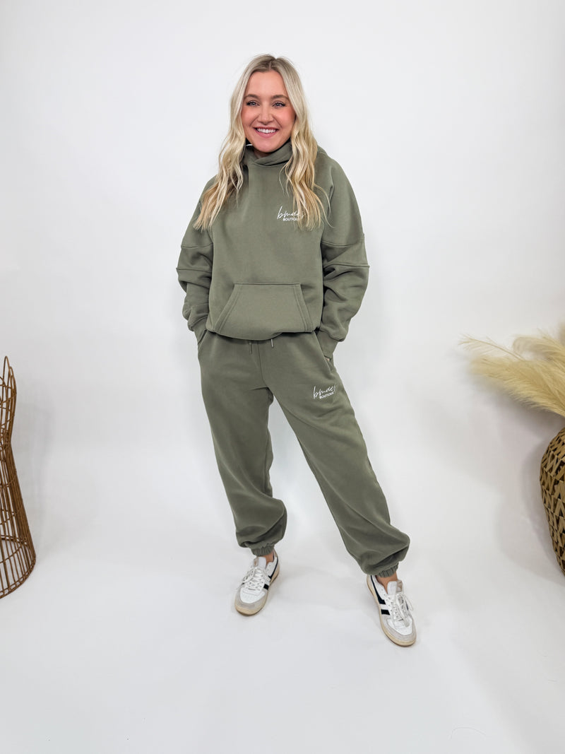 Olive green fleece-lined luxury lounge Bmaes hoodie with embroidered Bmaes Boutique logo, drop shoulders, kangaroo pocket, and ribbed details. Perfect for cozy lounging or pairing with the matching joggers for a stylish, warm set from Bmaes Boutique.