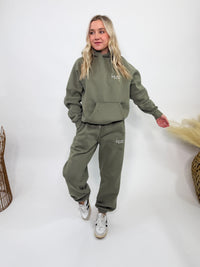 Olive green fleece-lined luxury lounge Bmaes hoodie with embroidered Bmaes Boutique logo, drop shoulders, kangaroo pocket, and ribbed details. Perfect for cozy lounging or pairing with the matching joggers for a stylish, warm set from Bmaes Boutique.