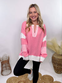 Pink Polo Preppy Style Sweater with ivory stripe patches on the sleeves and neckline, featuring a collared split neck design, long sleeves, high-low cut, and oversized fit, made of 100% polyester.