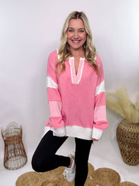 Pink Polo Preppy Style Sweater with ivory stripe patches on the sleeves and neckline, featuring a collared split neck design, long sleeves, high-low cut, and oversized fit, made of 100% polyester.