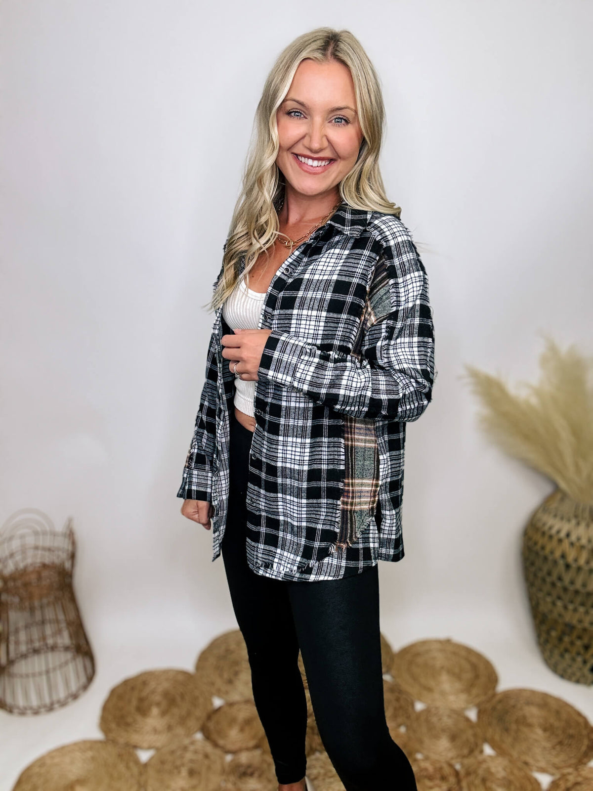 Black and white plaid flannel shirt with subtle olive, featuring frayed hem details, button-down front, and long sleeves, styled with a basic tank or graphic tee.