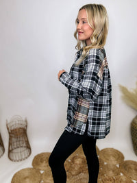 Black and white plaid flannel shirt with subtle olive, featuring frayed hem details, button-down front, and long sleeves, styled with a basic tank or graphic tee.
