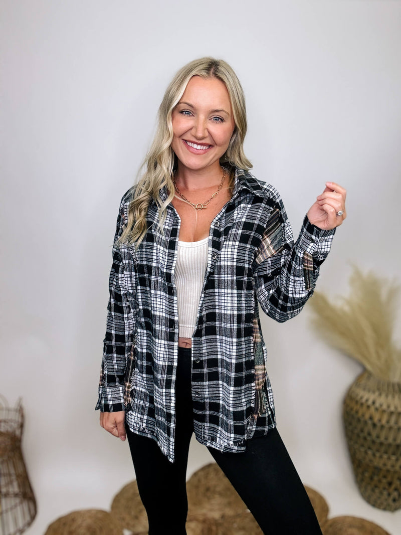 Black and white plaid flannel shirt with subtle olive, featuring frayed hem details, button-down front, and long sleeves, styled with a basic tank or graphic tee.
