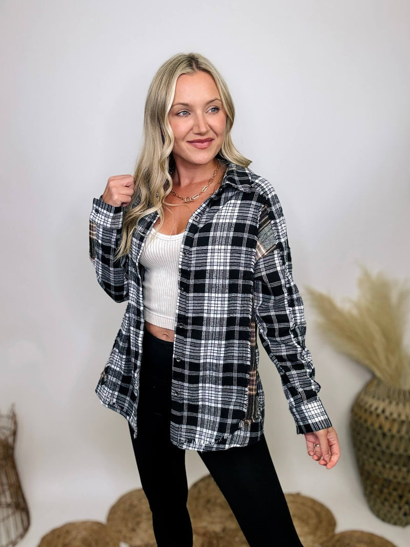 Black and white plaid flannel shirt with subtle olive, featuring frayed hem details, button-down front, and long sleeves, styled with a basic tank or graphic tee.
